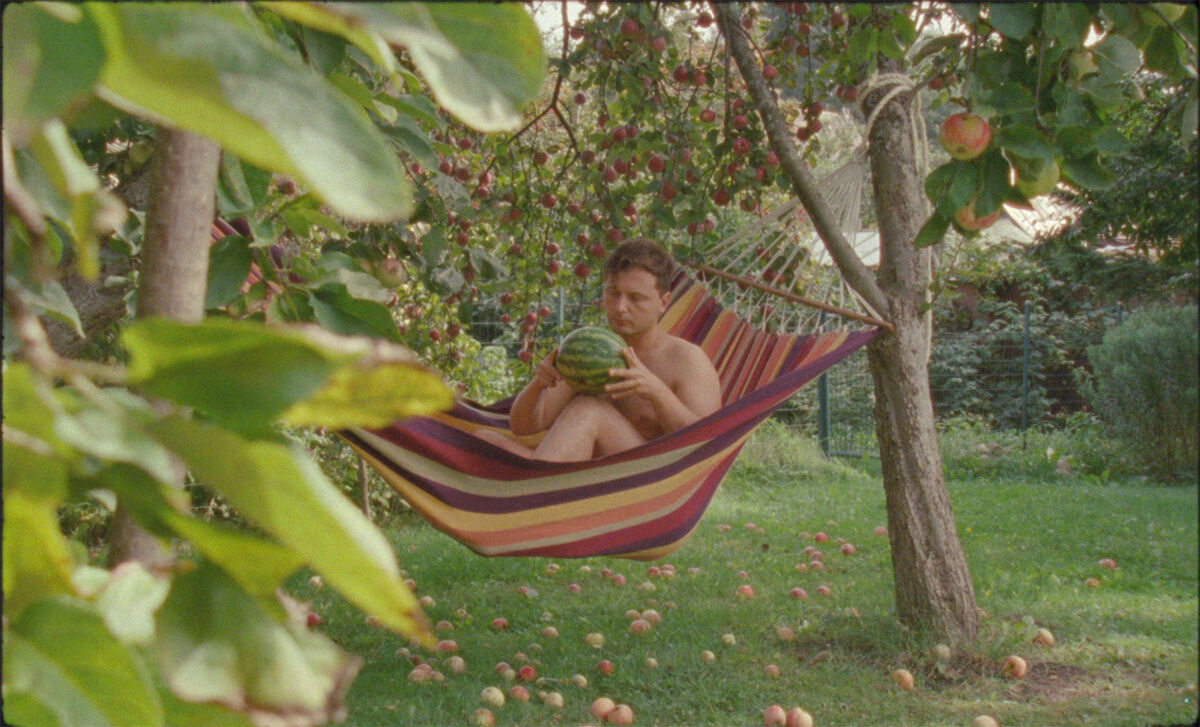 Man sitting in a hammock holding a watermelon