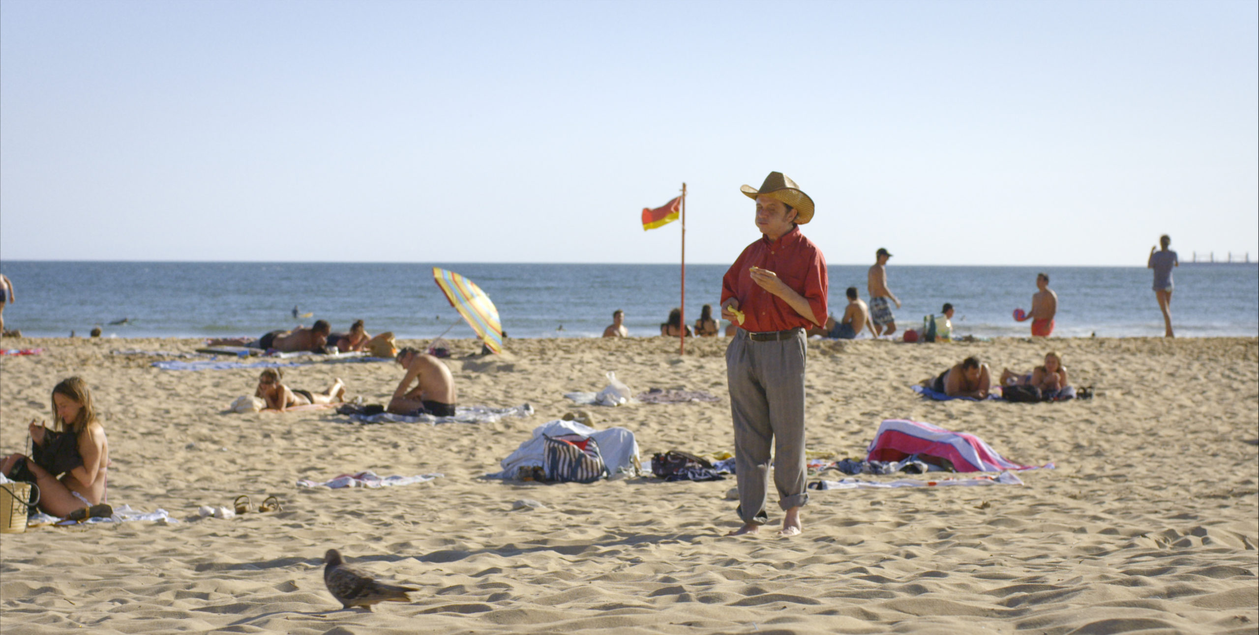 Man with cowboy hat standing on a crowded beach