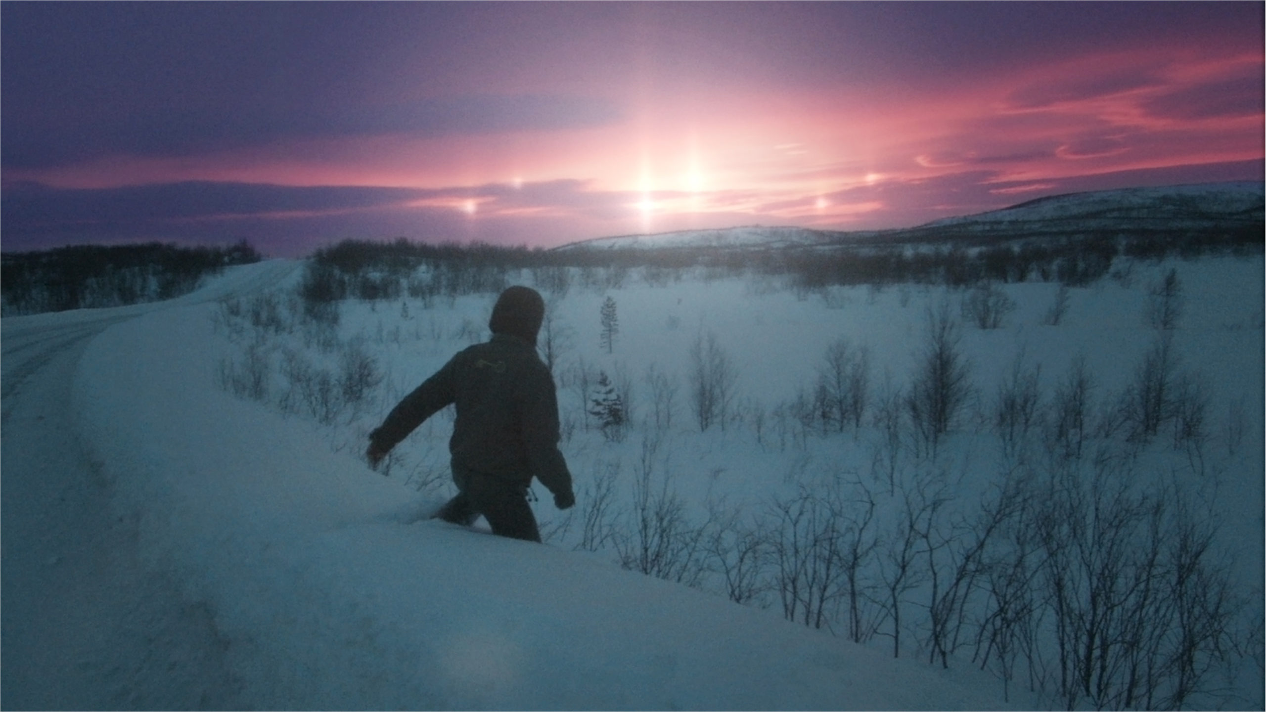 Snowy landscape with brightly lit sky with mysterious lights. Person running down a snowy hill