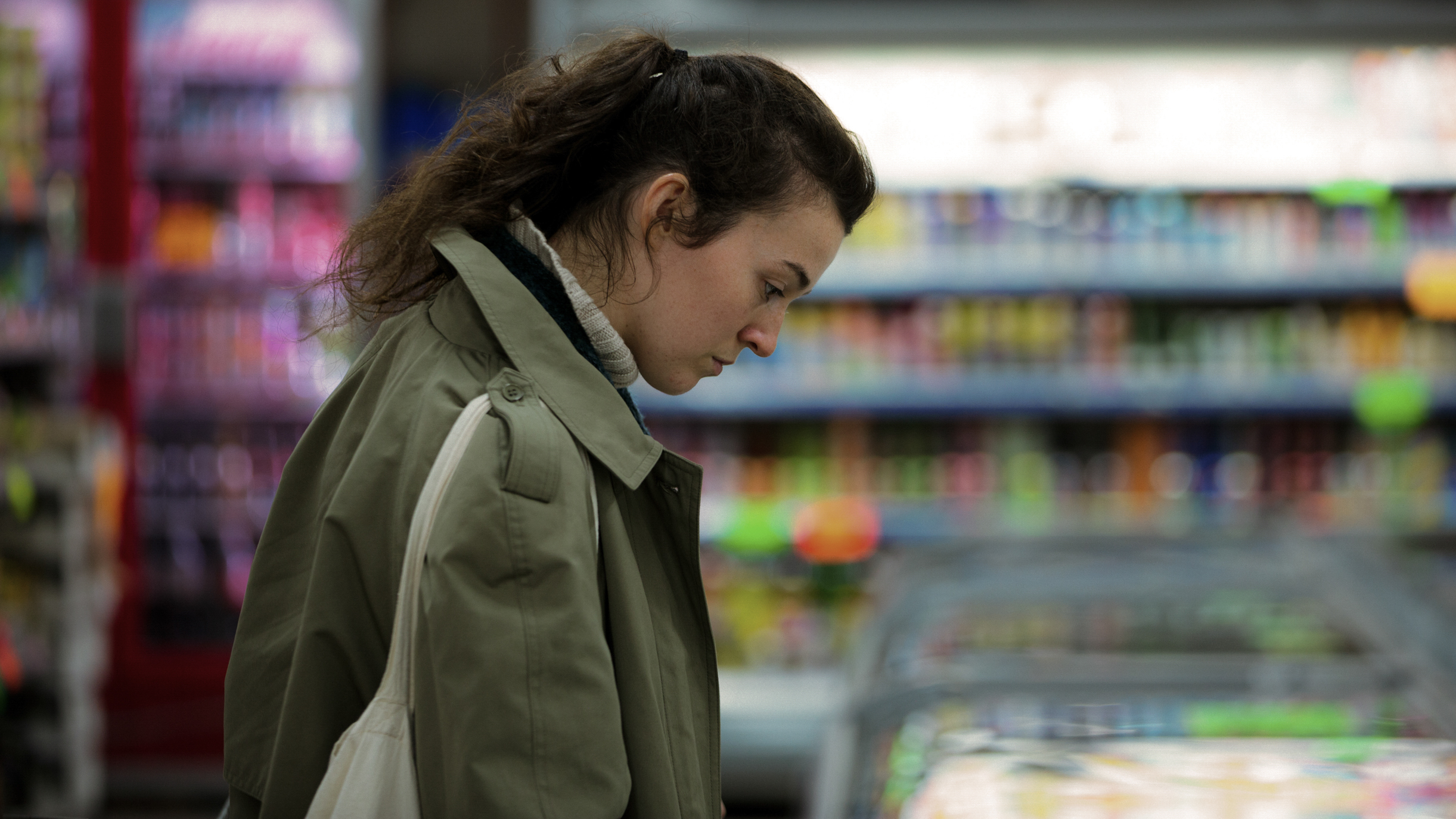 Woman in supermarket, looking into a fridge