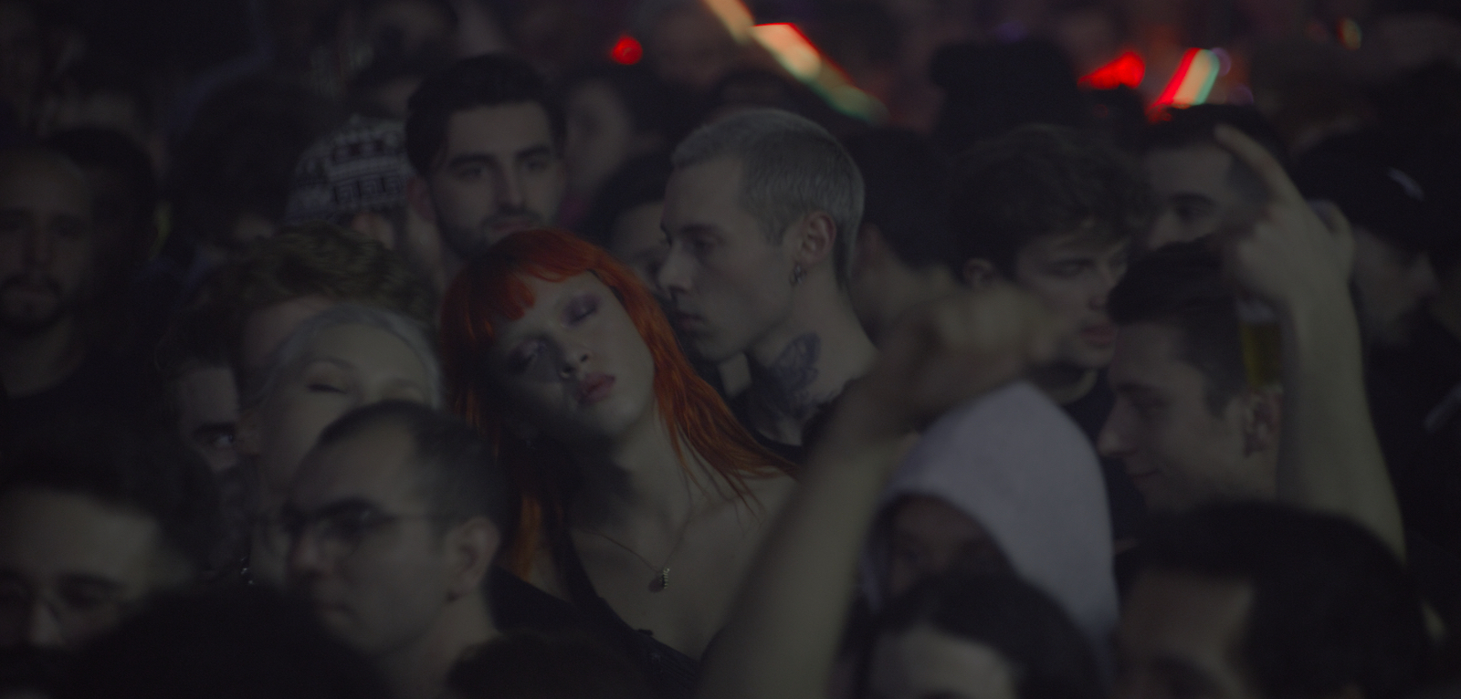 photo of a packed dancefloor, in the centre is someone with closed eyes and long orange hair