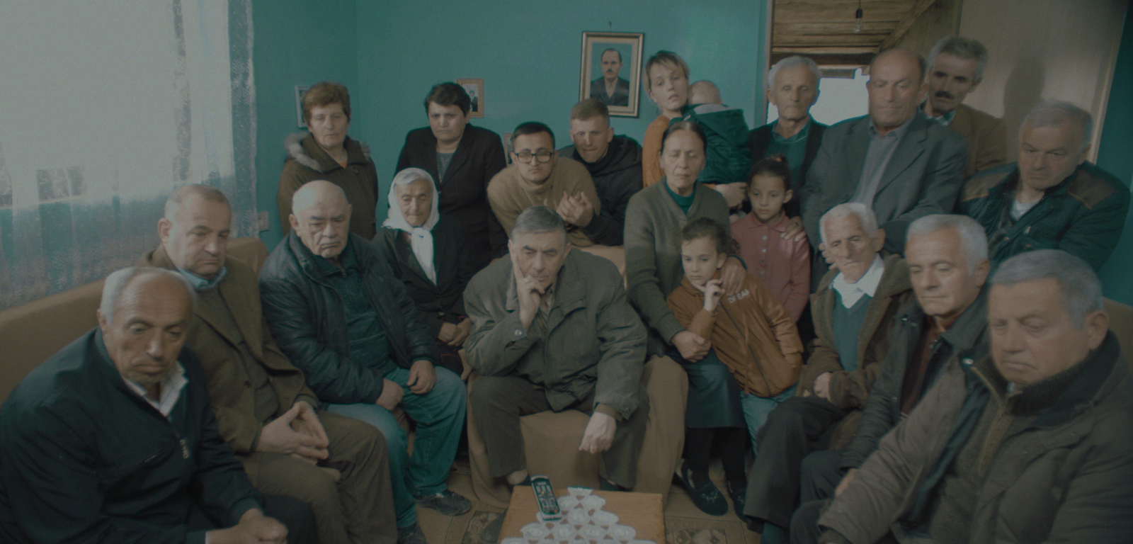 photo of 20 people of all ages, all staring at something in the living room which is outside of the image