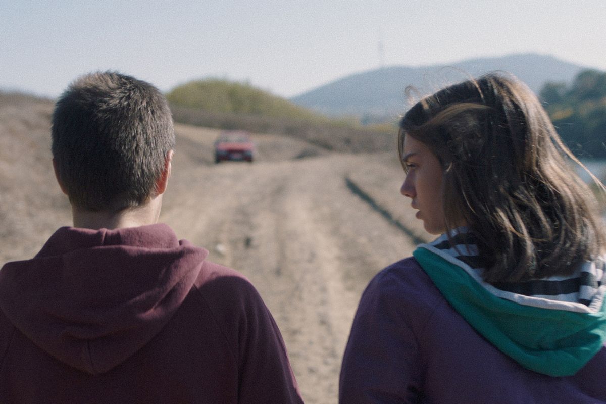film still of teen-aged couple from behind on dirtroad