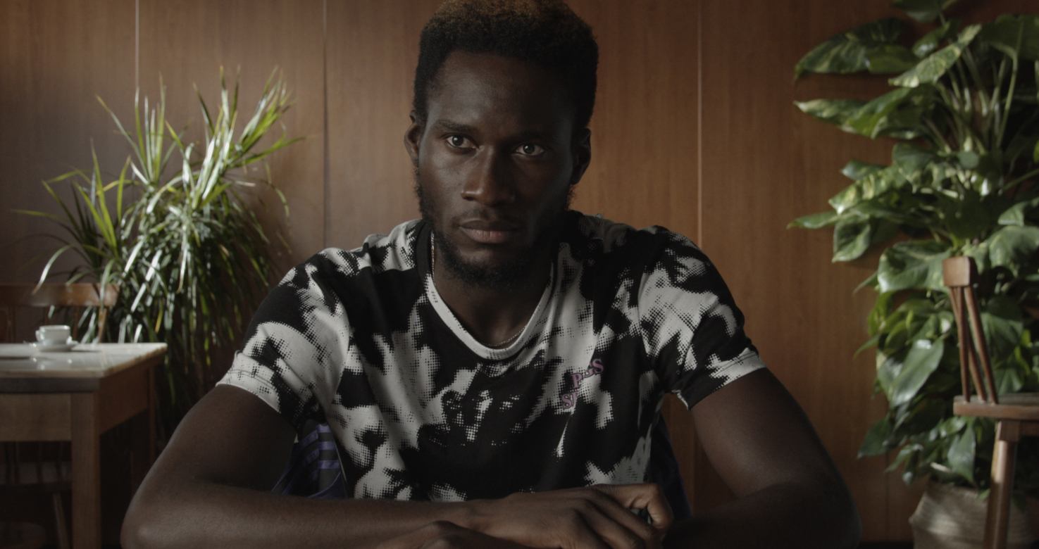 still of black man sitting at table