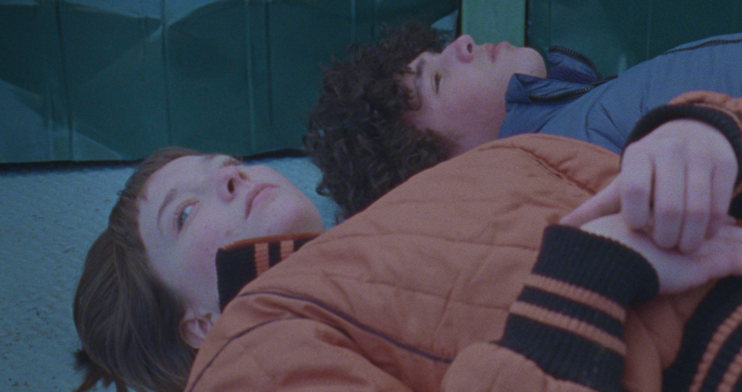 Still of two teenagers lying on floor