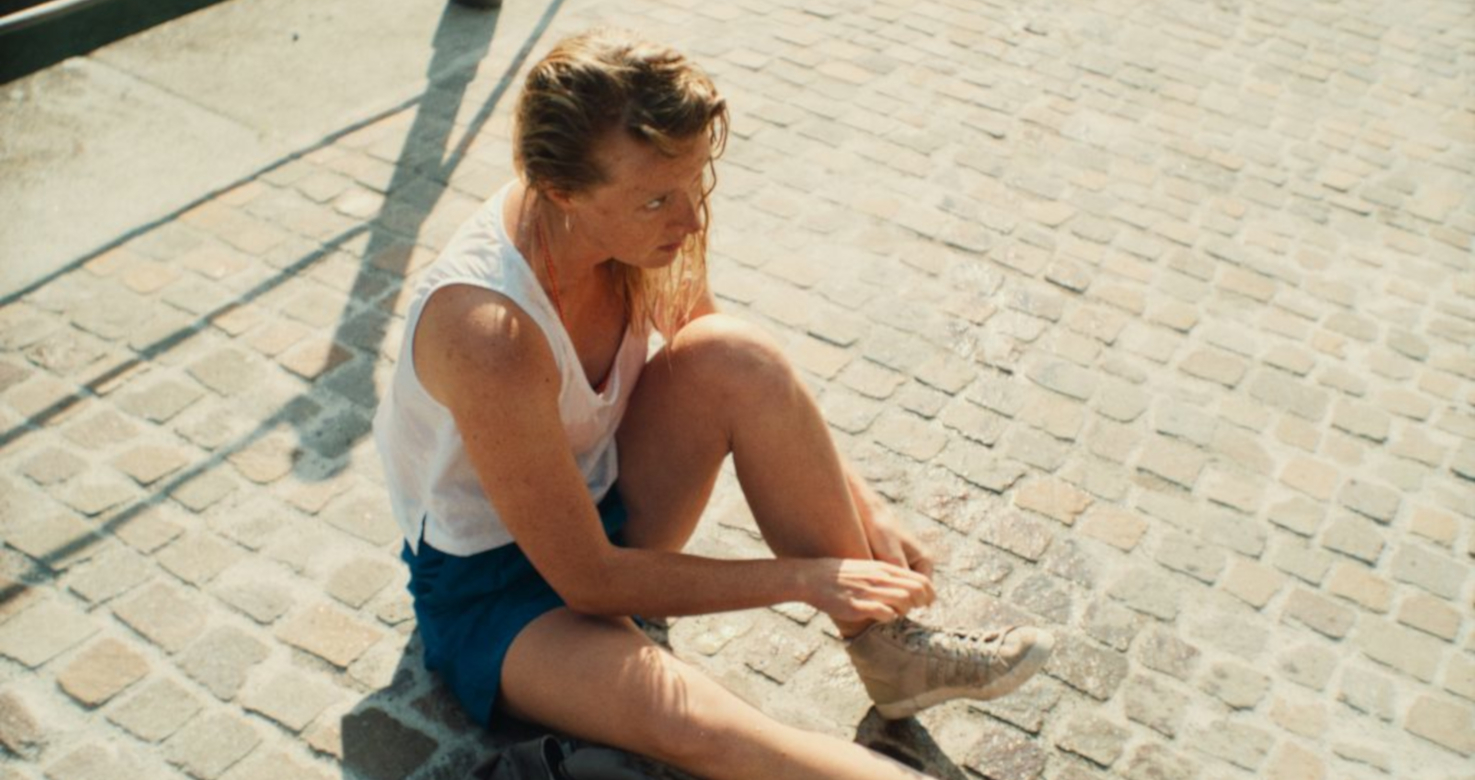 Young woman sitting on a street tying her shoes