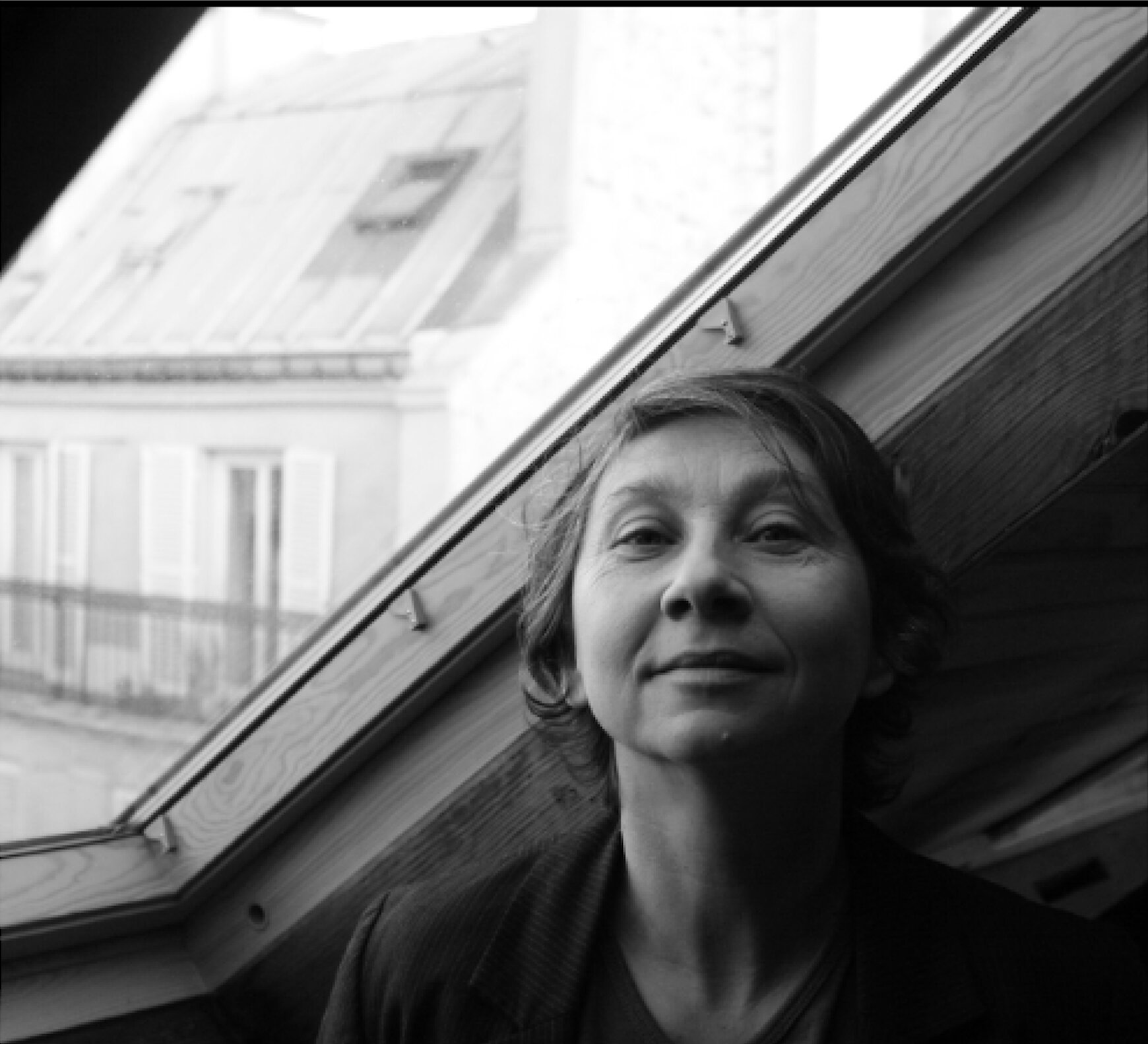 b&w photo of person under roof window